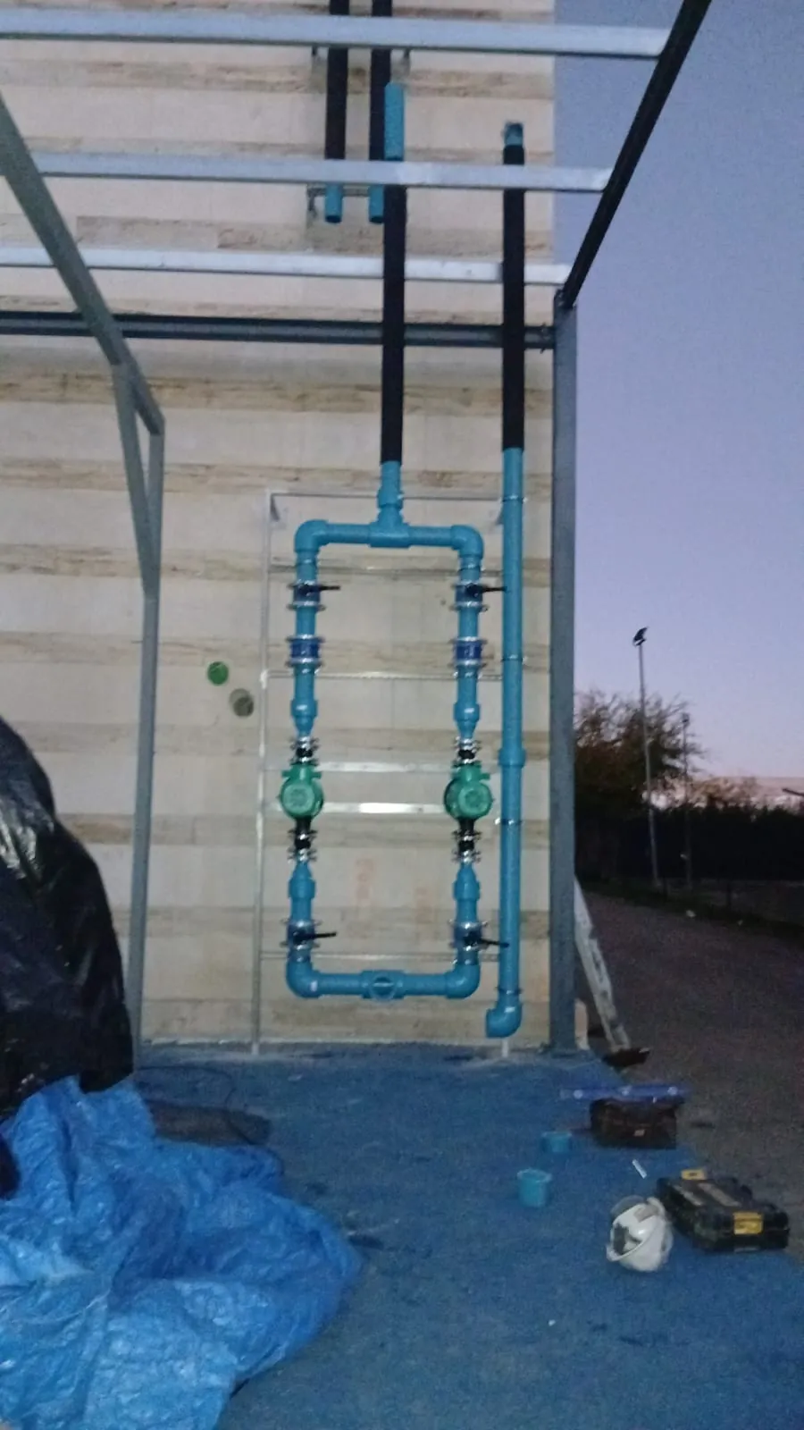 Colector de tuberías azules con bombas circuladoras sobre fachada